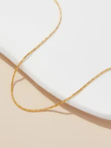 Macrodetail van de textuur van een minimalistische gouden titaniumstalen halsketting zonder hanger