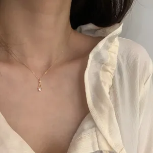 Delicado collar con colgante de gota y circonitas brillantes en fina cadena dorada detalle.