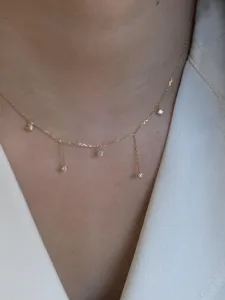 Delicate gold-tone pendant necklace with sparkling cubic zirconia charms for elegant details.