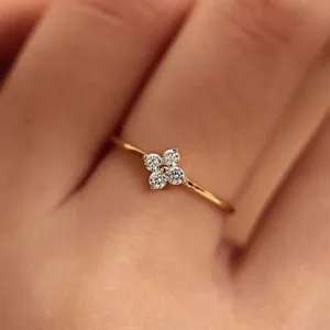 Macro detail of the delicate four-leaf clover ring showing sparkling stones worn on finger.
