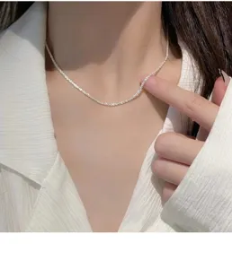 Close-up detail of sparkling silver clavicle chain worn on neck, elegant delicate design.
