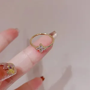 Close-up detail shot of a delicate gold clover ring featuring sparkling cubic zirconia stones.