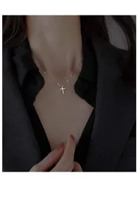 Gedetailleerde close-up van een minimalistische zilveren kruis hanger ketting om de nek.