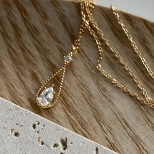Detalle de collar gota de circonita dorada, cadena delicada, colgante brillante