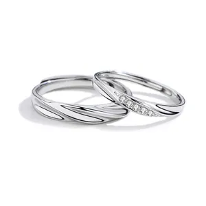 Conjunto de anillos de pareja de plata con diseño de ondas y piedras brillantes, elegantes.
