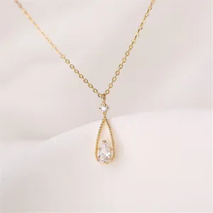 Primer plano de detalle del elegante collar con colgante de gota y circonitas brillantes.