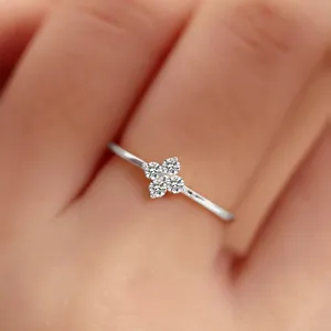 Close-up of a delicate sterling silver four-leaf clover ring with sparkling stones on finger.