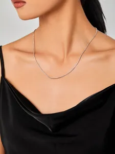Detailopname van een minimalistische zilveren vossenstaart ketting om de nek van het model