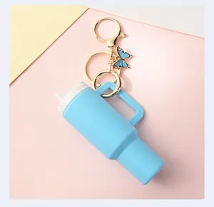 Mini tumbler keychain detailed close-up, cute portable cup pendant with butterfly charm.