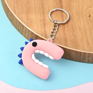 Gros plan détaillé d'un joli porte-clés alphabet rose avec dents et épines de dinosaure.