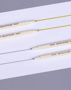 Detailed macro view of gold and silver metallic markers drawing glossy lines on paper