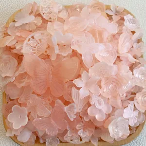 Primo piano di ciondoli rosa in resina a forma di farfalla e fiore per lavori fai da te.