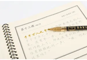 Close-up of golden metallic marker pen writing on a spiral notebook