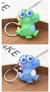 Vue détaillée de porte-clés dinosaure de dessin animé mignon en vert et bleu avec silicone.