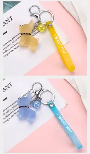 Close-up detail of cute cartoon french bulldog keychain with strap and bell charm in multi colors.