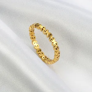 Close-up of gold stainless steel ring featuring a continuous dollar sign pattern on white silk.
