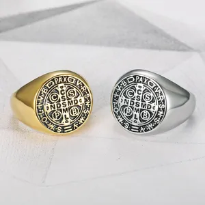 Close-up of vintage stainless steel signet rings with detailed religious engraving.