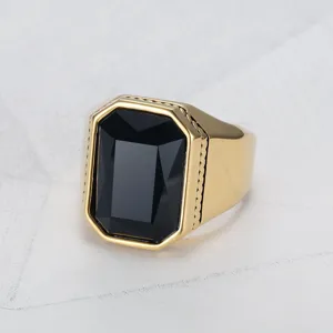 Detailaufnahme eines quadratischen Rings mit schwarzem Edelstein und goldener Titanium-Oberfläche.