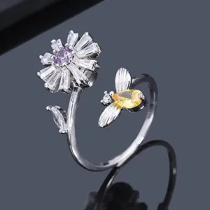 Makroansicht eines verstellbaren Rings mit funkelndem Gänseblümchen- und Bienendesign.
