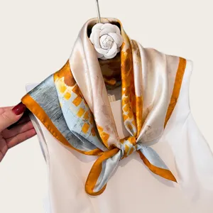 Silk square scarf detail view, yellow and grey abstract print, elegant neckerchief style.