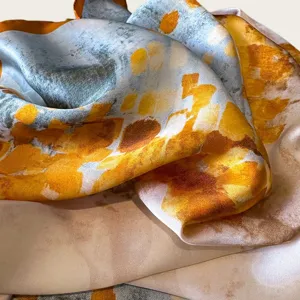 Silk square scarf detail showing abstract artistic watercolor print pattern, smooth luxury fabric feel.