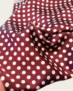 Detail shot of burgundy polka dot silk scarf, soft fabric texture and elegant drape.