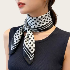 Close-up detail of a classic black and white polka dot silk scarf elegantly tied.