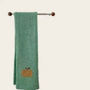 Green knitted scarf detail view, featuring a cute apple pattern and cozy texture for autumn.
