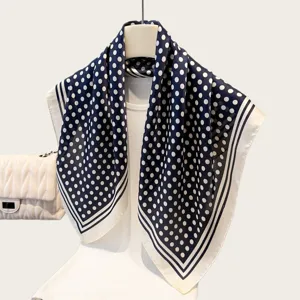 Closeup detail of the elegant navy blue and white polka dot square scarf with striped border.