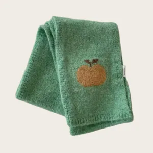 Close-up of green knitted scarf featuring cute embroidered apple detail, soft cozy texture.