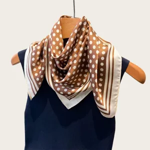 Detailed shot of a brown and white polka dot silk square scarf, elegant retro neckerchief style.
