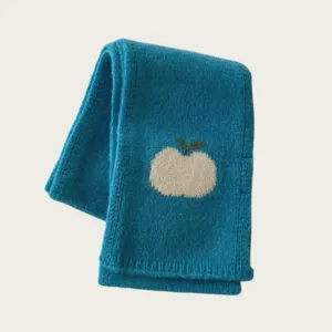 Blue knitted wool scarf detail with cute white apple pattern, cozy winter accessory.