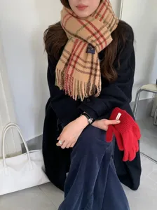 Detailaufnahme des klassischen Karomuster-Schals im Winter kombiniert mit einem schicken Mantel.