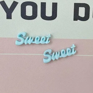 Primo piano di ciondoli con lettere Sweet in resina azzurra, ideali per progetti artigianali e fai-da-te.