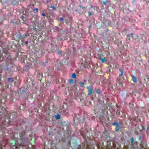Vue en gros plan de cœurs roses en argile polymère, perles et paillettes holographiques pour DIY.