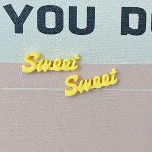 Dettaglio in primo piano di ciondolo in resina lettera sweet giallo accessorio tazza