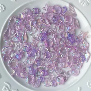 Gros plan de détails de charms en résine océanique irisée mélangée avec coquillages et étoiles.