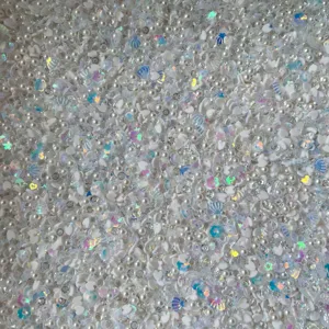 Gros plan détaillé de perles blanches, de cœurs en argile et de sequins iridescents.