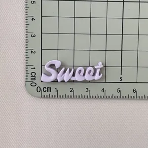 Vista dettagliata del ciondolo lettera sweet in resina viola, accessorio artigianale DIY e adesivo.