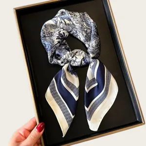 Detail shot of the elegant blue and white printed silk scarf displayed in a black tray.