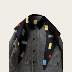 Close-up detail of the colorful patch knit shawl paired with classic herringbone outerwear.