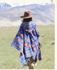 Dettaglio mantella con cappuccio boho, motivo geometrico etnico in maglia e orlo con frange.