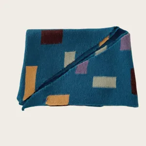 Detailed view of a blue knitted scarf featuring stylish geometric color block patterns.