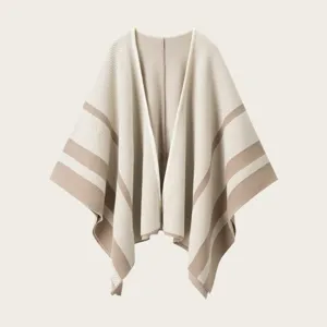Close-up detail of the cozy knitted striped poncho shawl in beige and brown, elegant texture.