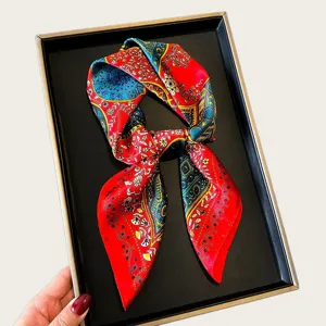 Detail shot of a vibrant red and blue silk scarf featuring ornate baroque patterns displayed neatly.