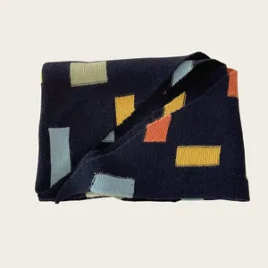 Close-up detail of a stylish navy knit scarf featuring colorful geometric block patterns.