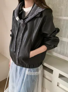 Vista detallada de una elegante chaqueta de cuero sintético negro combinada con bufanda.