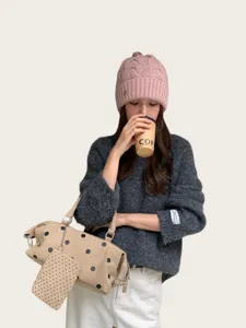 Nahaufnahme der stilvollen rosa Zopfstrick-Mütze am Model, kuschelige Wintertextur.