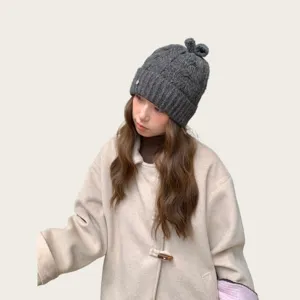 Graue Zopfstrick Mütze für Damen mit niedlicher kleiner Schleife oben und warmer Wolle.