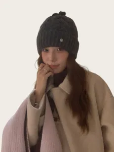 Nahaufnahme des koreanischen Strickmützen-Details mit süßer Schleife und Metall-Logo, gemütlich.